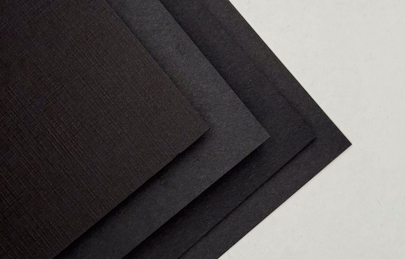 Stack of black cardstock sample sheets with a textured surface