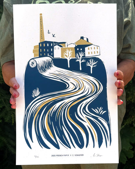 Person holding a print of a stylized cityscape with a river design.