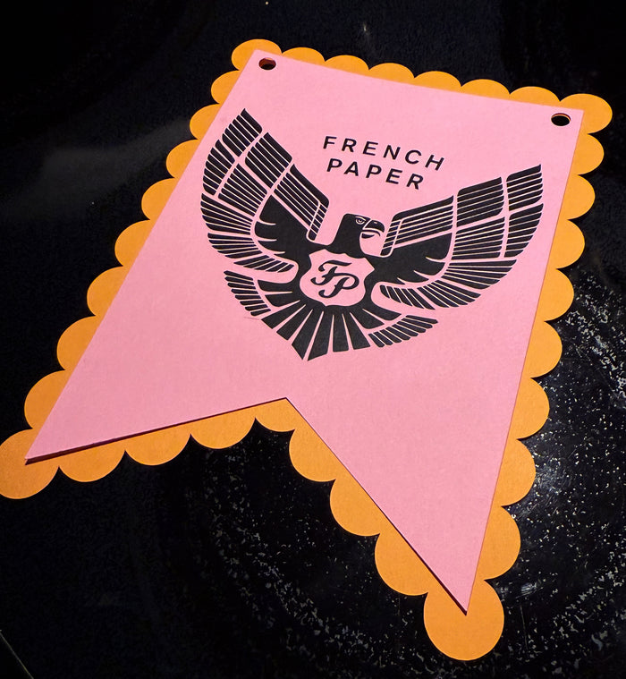 Pink paper flag with scalloped edge and 'French Paper' logo on a black background