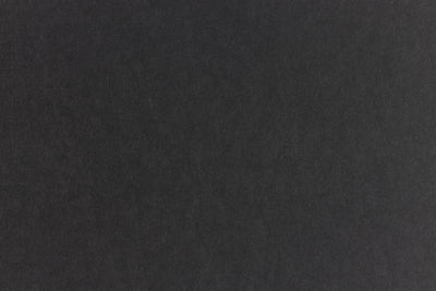 Subtly textured black paper viewed close up. 